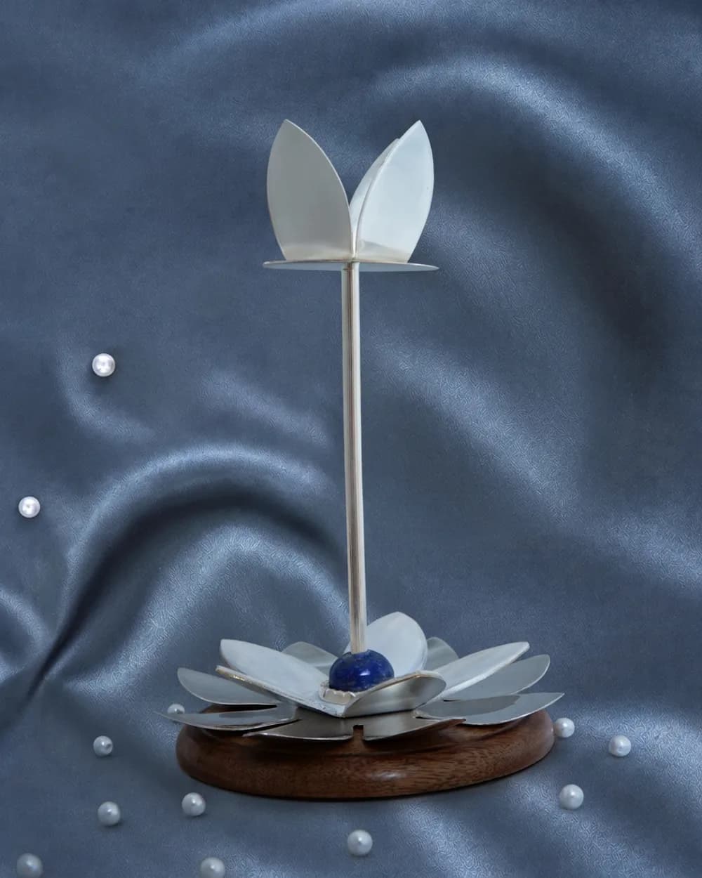 A tall silver-plated lotus candle holder rising from an open silver flower on a turned mango-wood base.