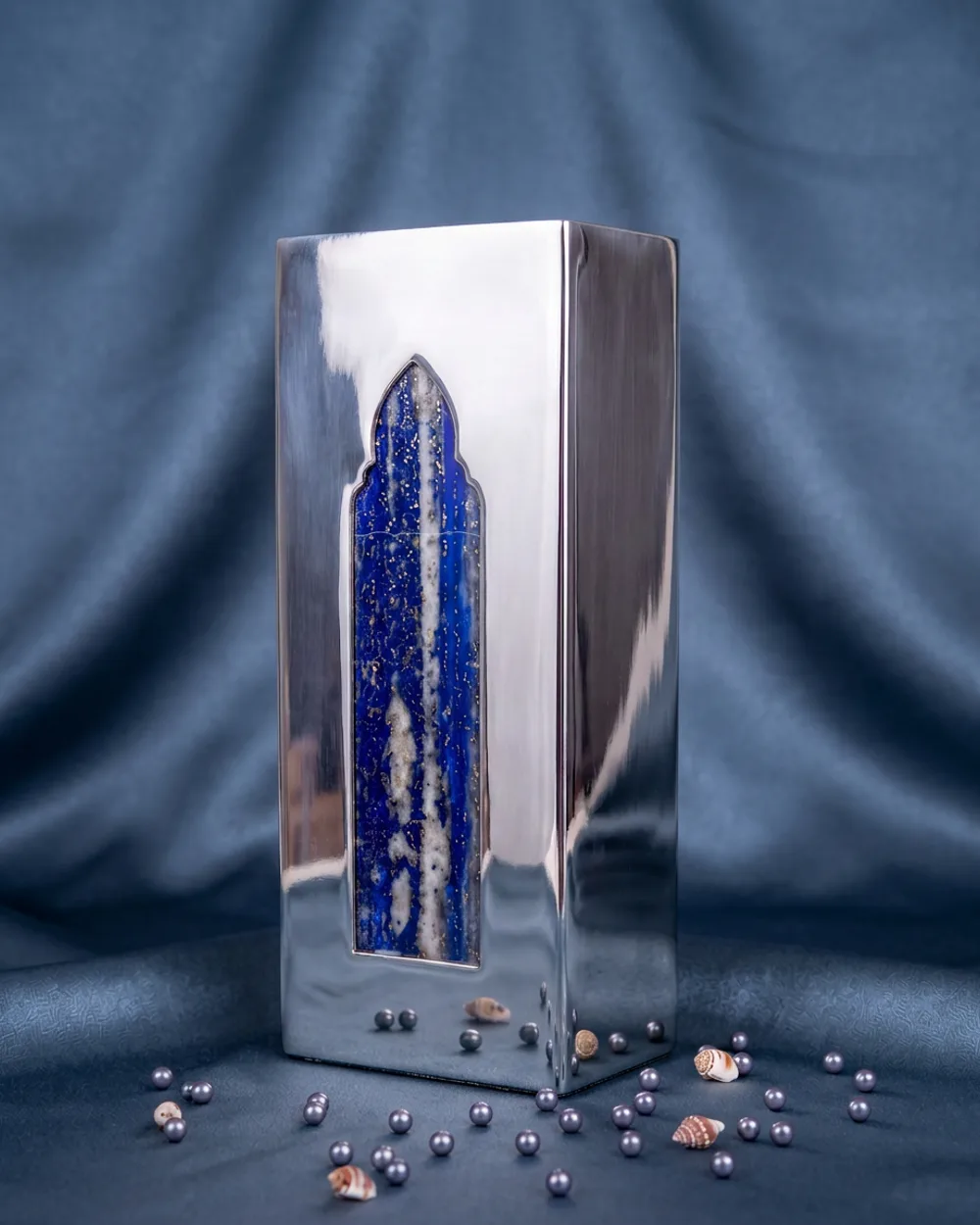 A tall mirror-polished silver-plated vase with an arched window of semi-precious lapis lazuli running its height.