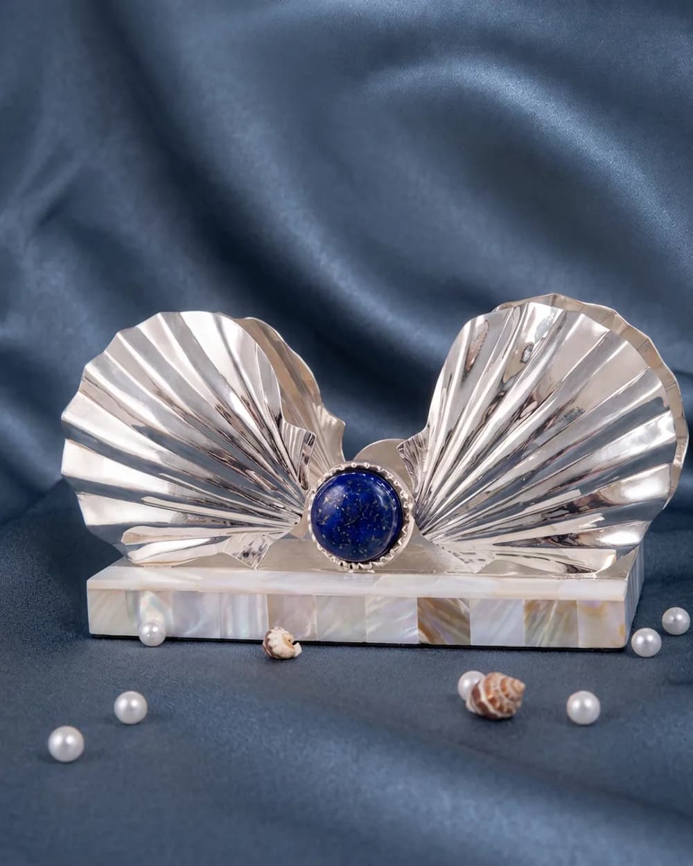 A silver-plated napkin holder shaped as two open scallop shells, meeting at a cabochon of semi-precious lapis lazuli.